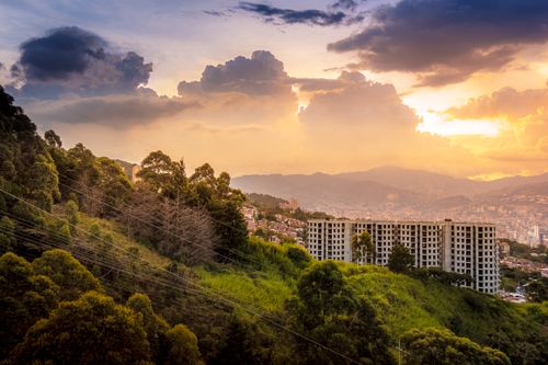 Free Captivating urban landscape with lush greenery and dramatic clouds at sunrise. Stock Photo