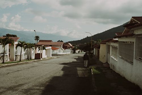 Free Quiet suburban street in Mérida, Venezuela, featuring tile-roofed houses and mountain views. Stock Photo