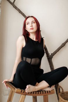 Young woman with pink hair posing elegantly in black outfit indoors.