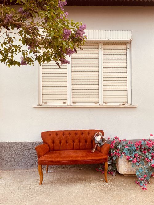 Free Rustic outdoor seating with pink blooms and decorative shutters, perfect for relaxation. Stock Photo