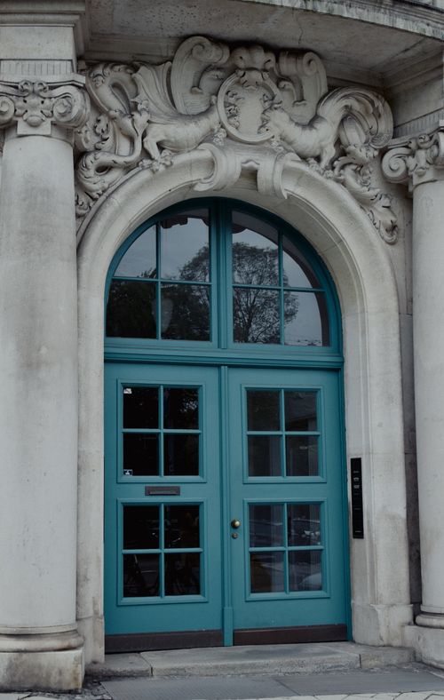 Free A striking blue door in an urban setting surrounded by intricate carved stonework and an arched frame. Stock Photo