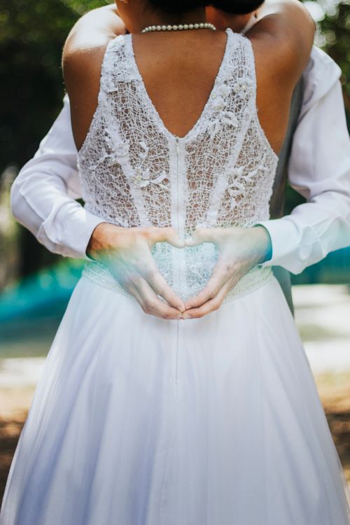 Free Bride and groom embracing outdoors, forming a heart shape with hands. Perfect for wedding themes. Stock Photo
