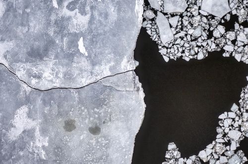 Free Aerial view of cracked ice on a frozen lake, showcasing dramatic winter patterns. Stock Photo