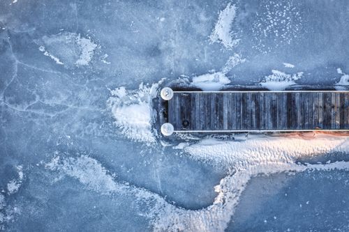 Free Aerial shot of a pier surrounded by frozen ice, showcasing winter's chill. Stock Photo