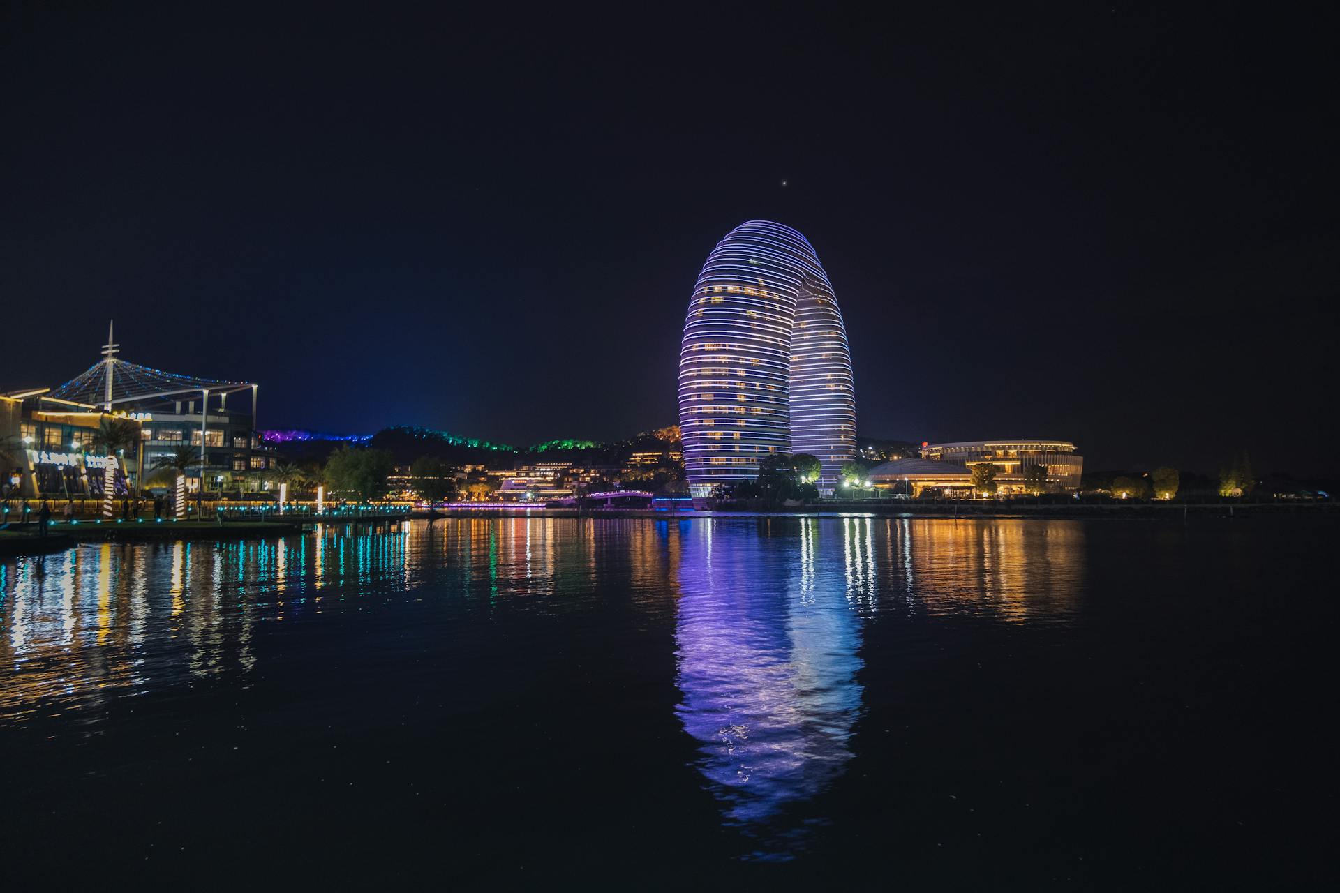 Illuminated Sheraton Huzhou Hot Spring Resort reflecting in water at night in China.