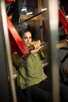A woman using gym equipment indoors focuses on her workout for fitness and health.