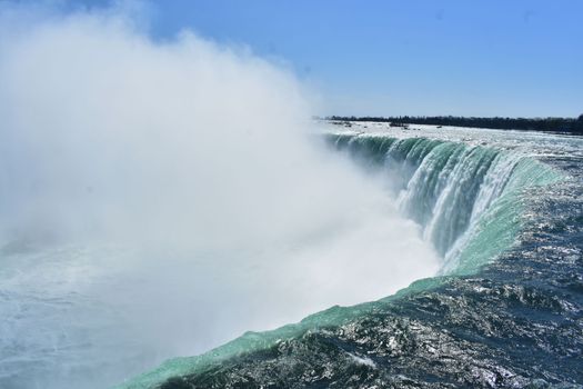 Capture the breathtaking Niagara Falls cascading under a vibrant blue sky.