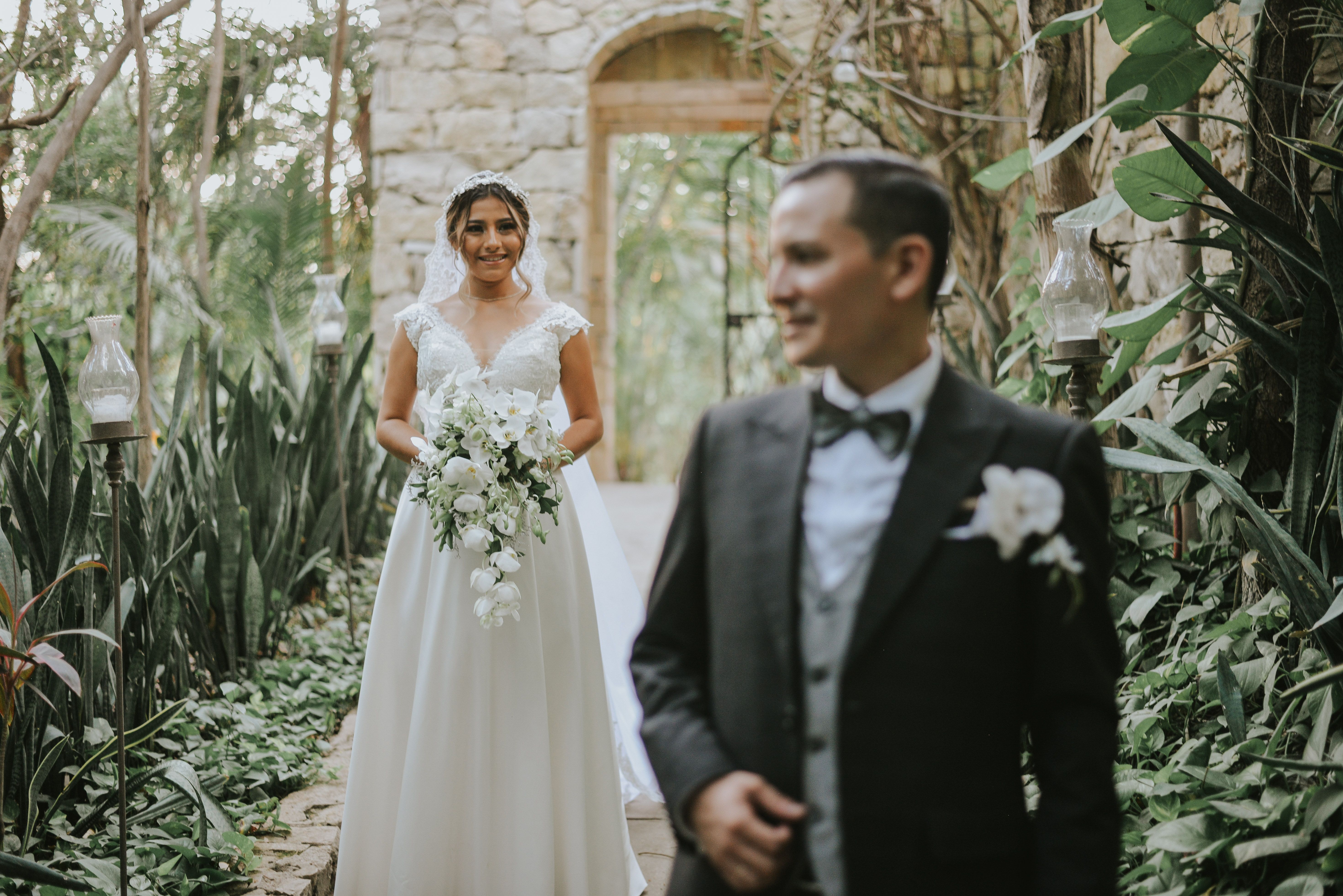 Bride and groom captured in elegant wedding attire amidst a lush botanical garden setting.