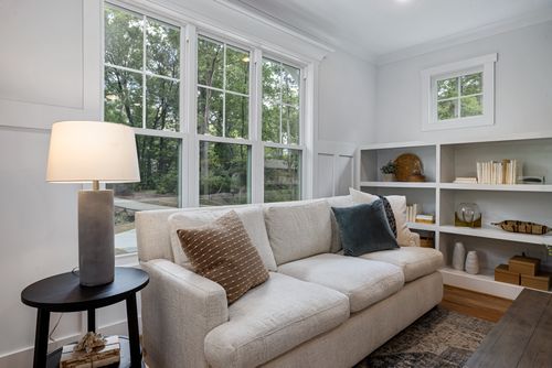 Free Inviting living room featuring a cozy sofa, large windows, and stylish decor. Stock Photo