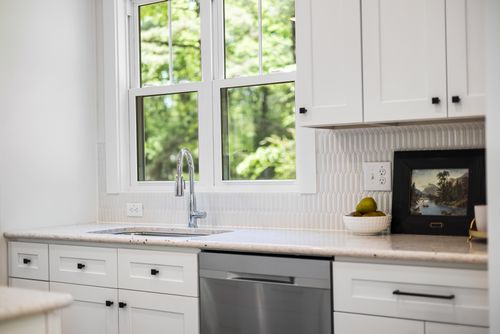 Free Contemporary white kitchen interior with natural light, featuring a sink and window view of greenery. Stock Photo