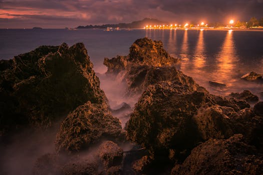 Stunning twilight seascape captured at Sipalay, Negros Island, Philippines, featuring illuminated rugged rocks and serene waters.