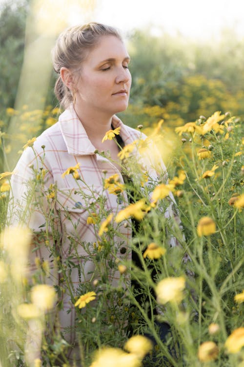 Woman in a Wild Meadow Enjoys the Smell of Flowers