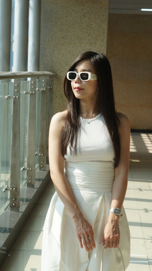 Photo of a Young Woman Wearing Sunglasses and a Dress