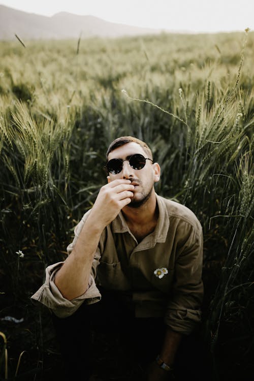 Man in Sunglasses Sitting on Field