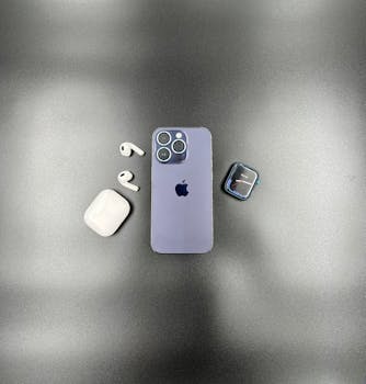 Flat lay of a smartphone, earbuds, and smartwatch, on a sleek surface, highlighting modern technology.