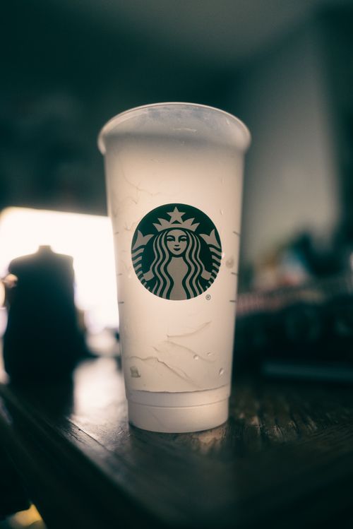 Free Close-up shot of a Starbucks-branded disposable cup on a table with light bokeh. Stock Photo