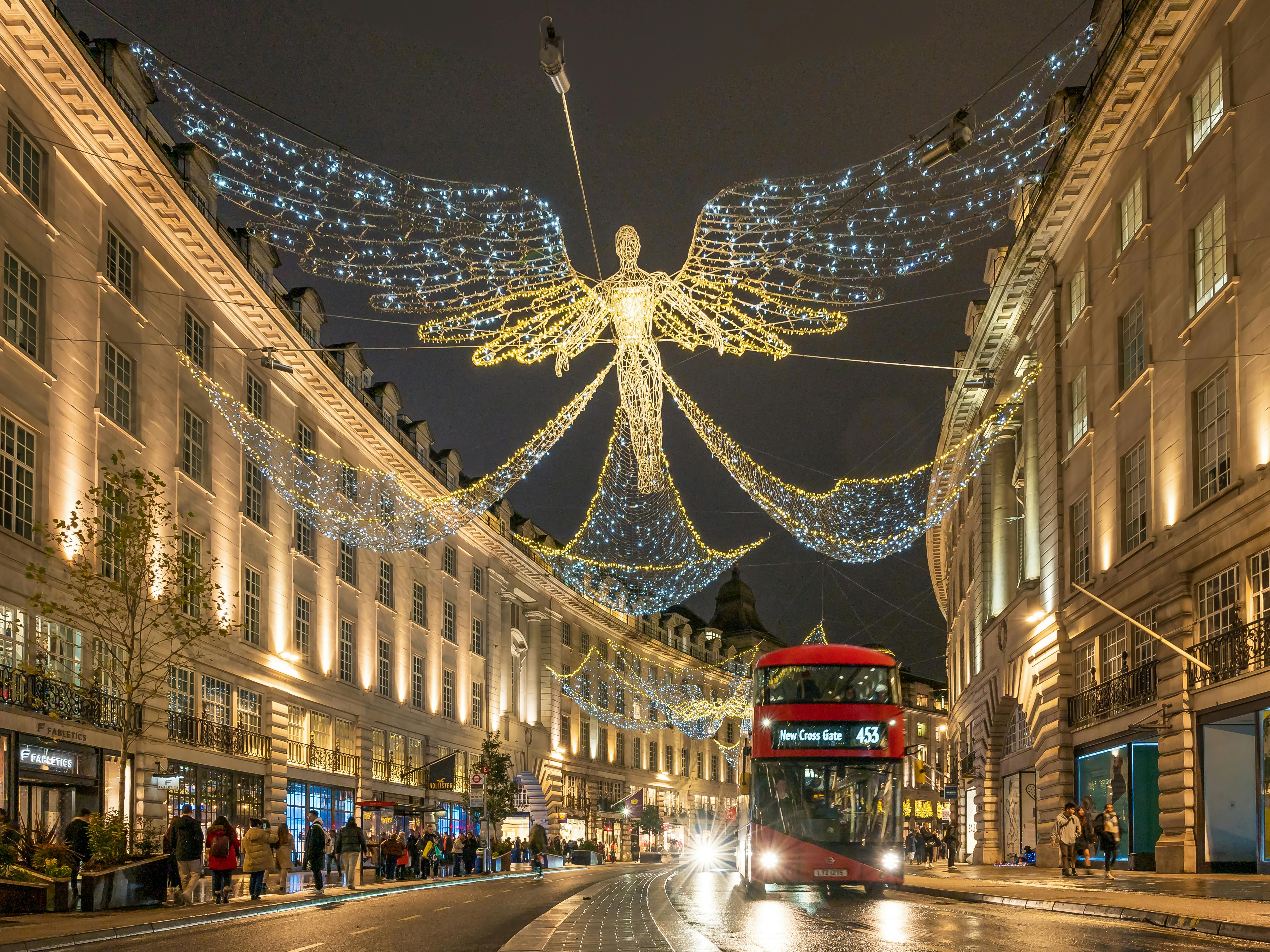 Free Stunning evening view of Regent Street in London, adorned with festive angel lights and iconic red double-decker bus. Stock Photo
