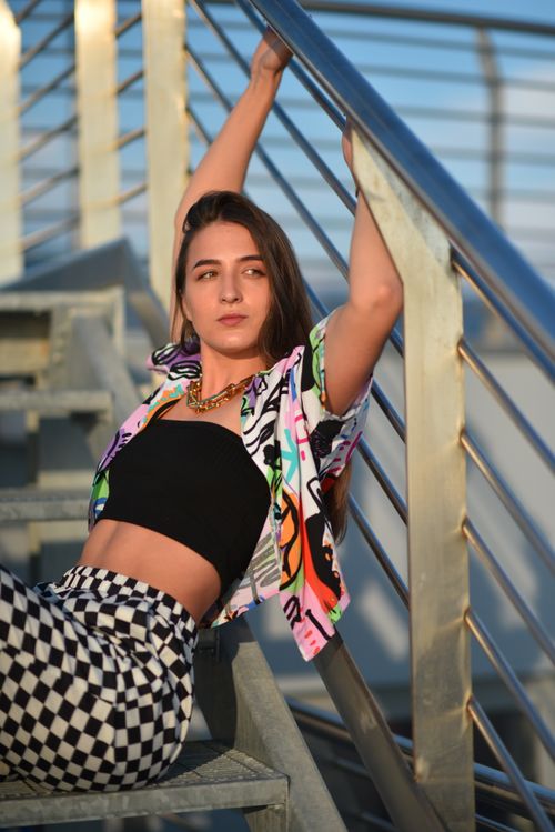 Free Youthful fashion model posing on a modern staircase in vibrant summer attire. Stock Photo