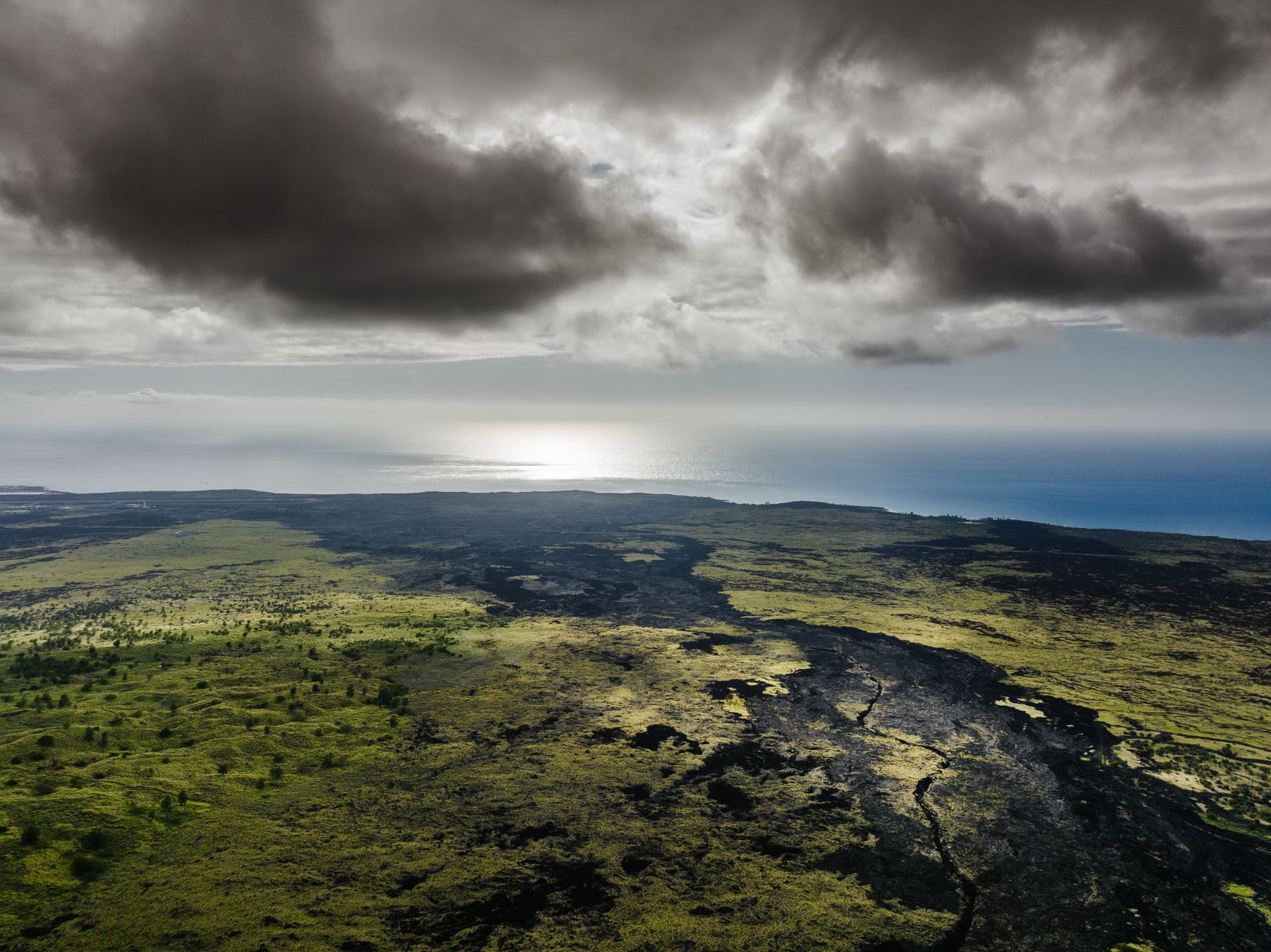 Aerial Big Island view: Hualalai Volcano near Kalaoa, where green slopes meet the deep blue Pacific Ocean.