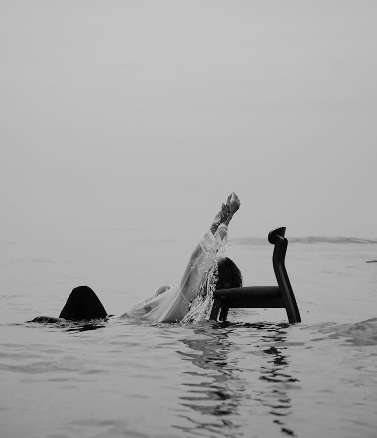 Woman Leaning On Chair In Water In Black And White