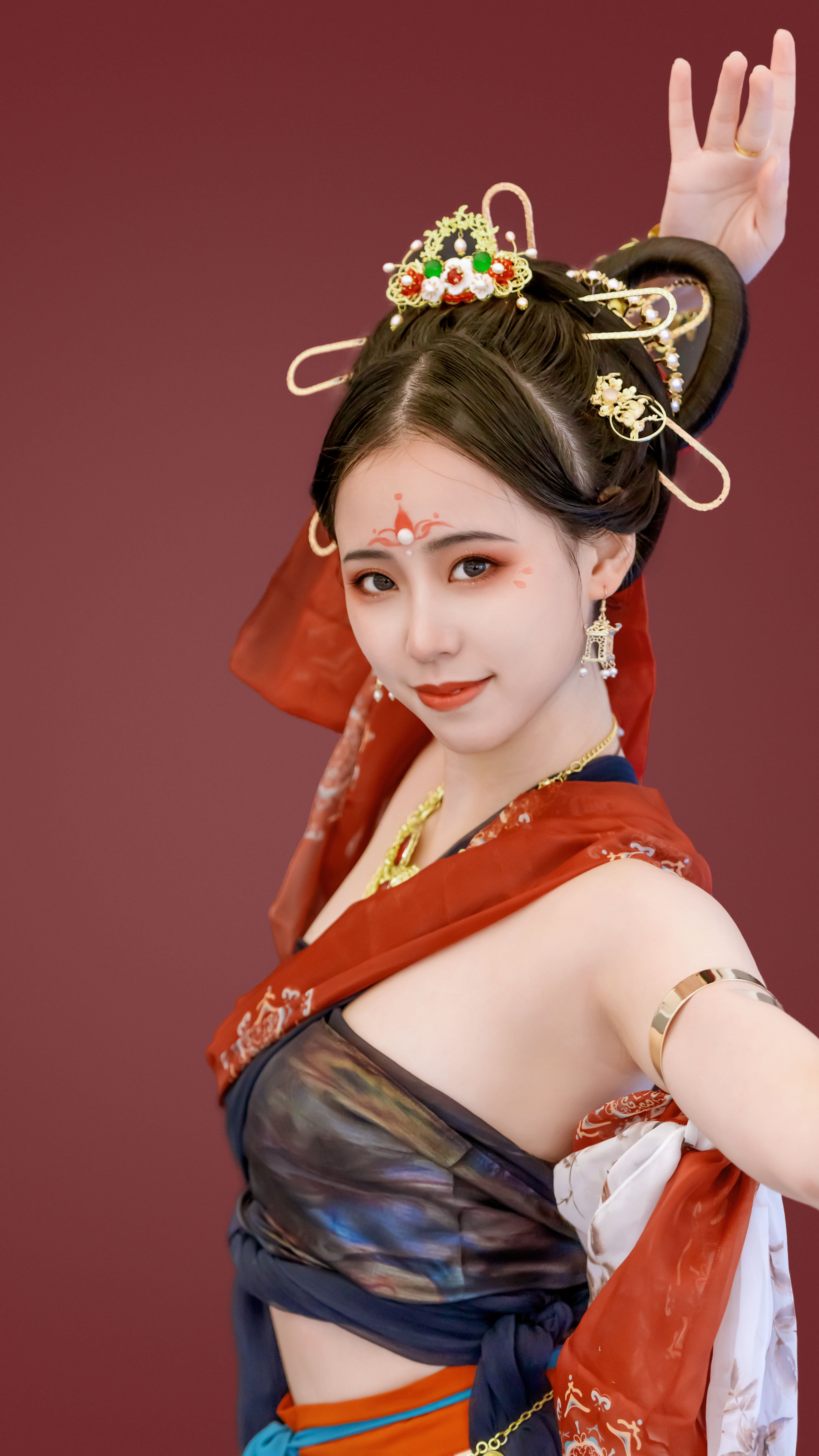 Portrait of a woman in traditional attire posing gracefully against a rich red background.