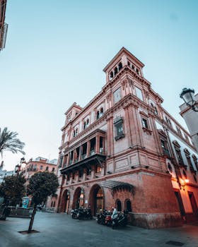 Capture of a historic architectural landmark in Seville, Spain at twilight with a clear sky.