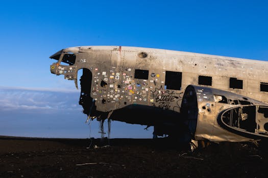 An old, abandoned airplane wreckage on a deserted land against a clear blue sky.