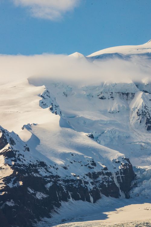 Free A breathtaking view of snow-covered mountain peaks with low-lying clouds on a sunny day. Stock Photo