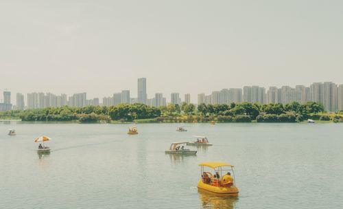 Free Peaceful city lake scene with pedal boats and skyline in the background. Stock Photo