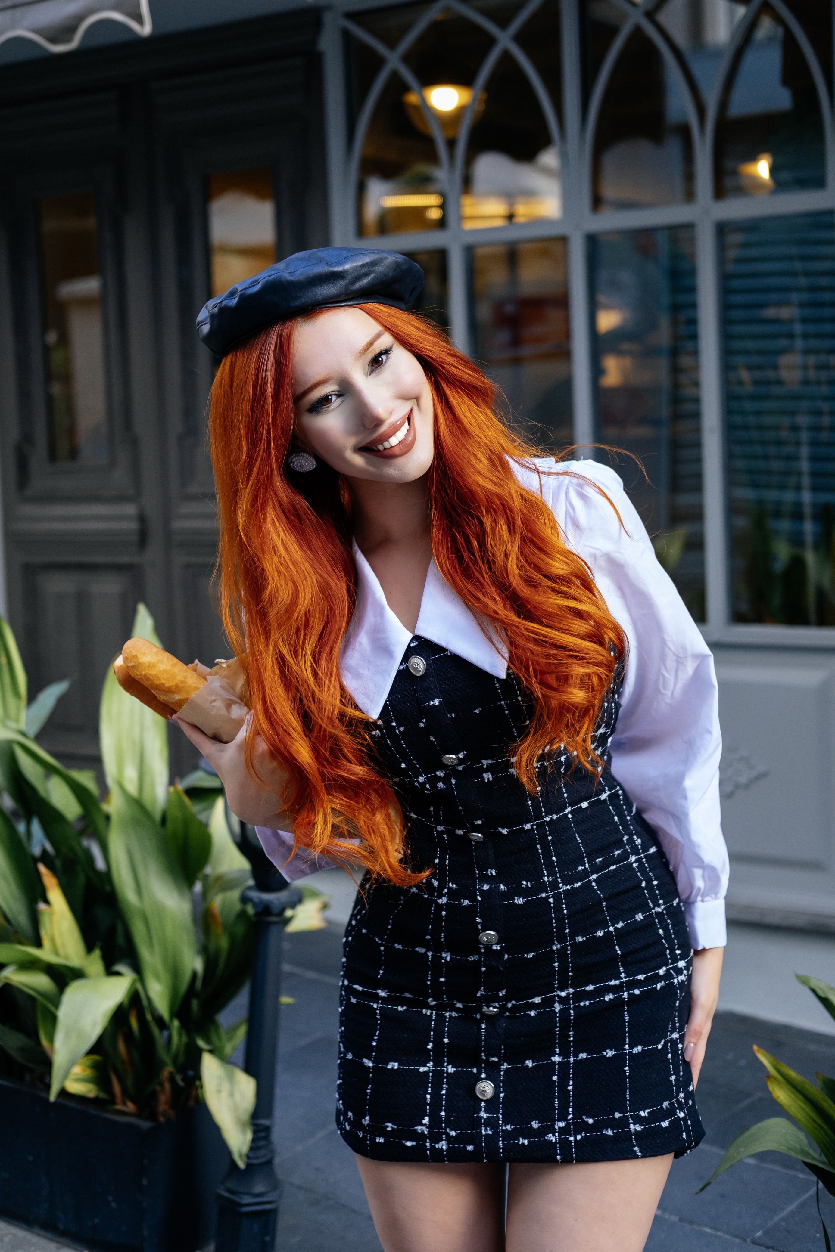 Elegant young woman with red hair savoring a baguette outside a stylish cafe in Türkiye.