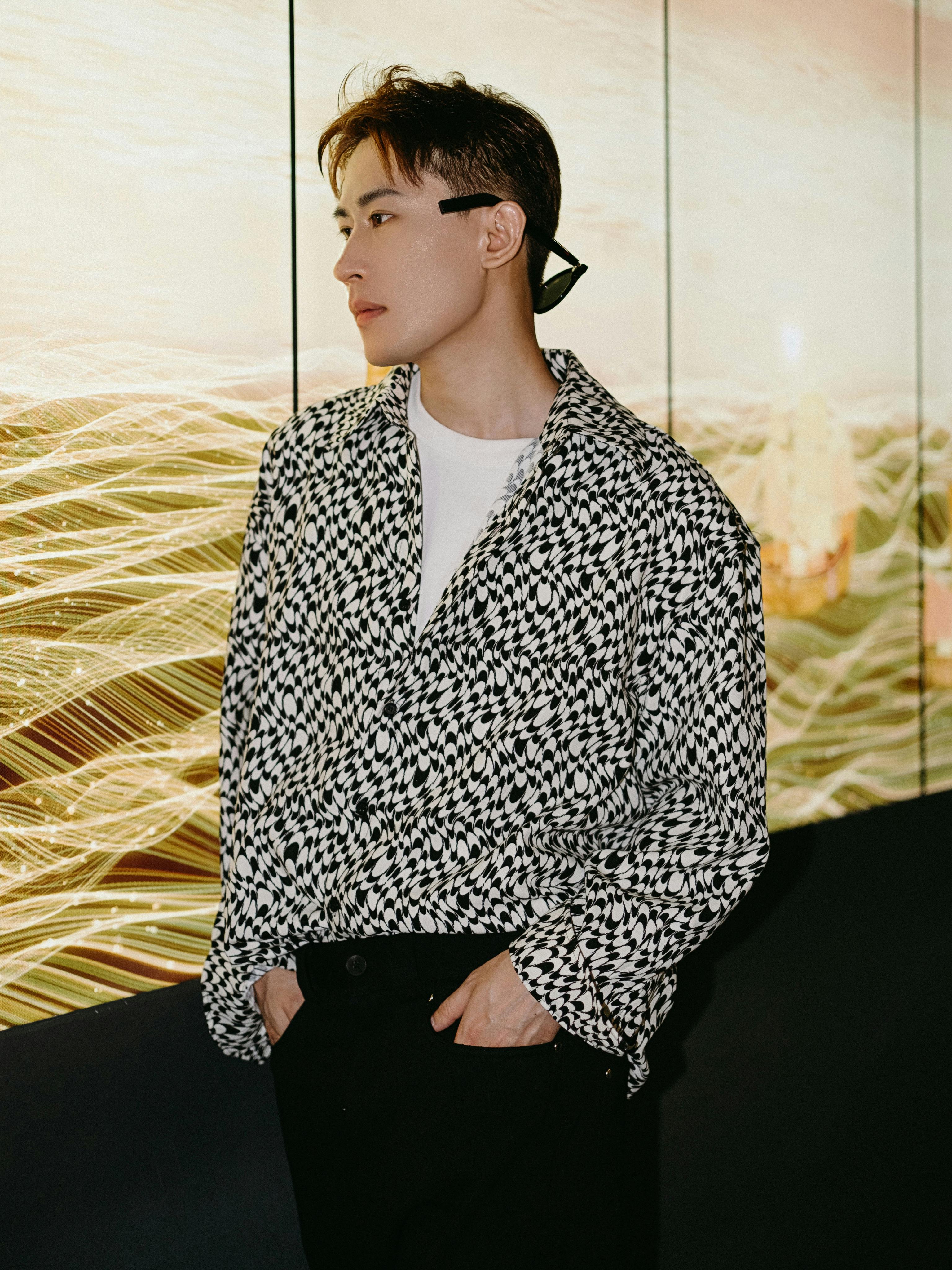 A fashionable adult man stands indoors with modern abstract background.