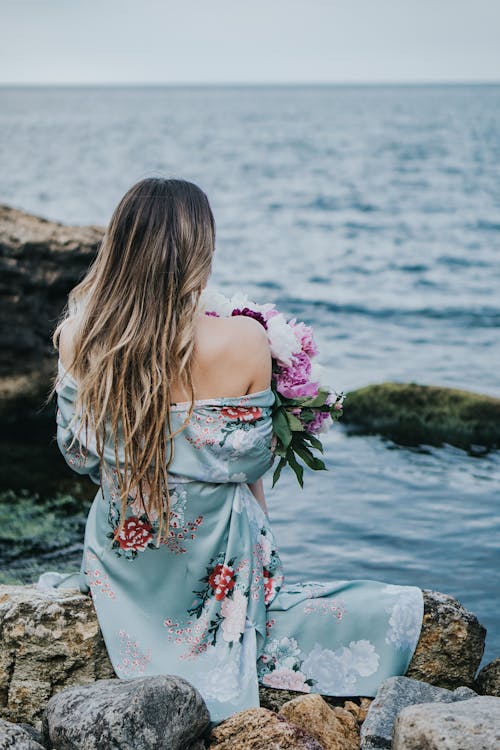 Back View of Blonde woman with Flowers on Sea Shore