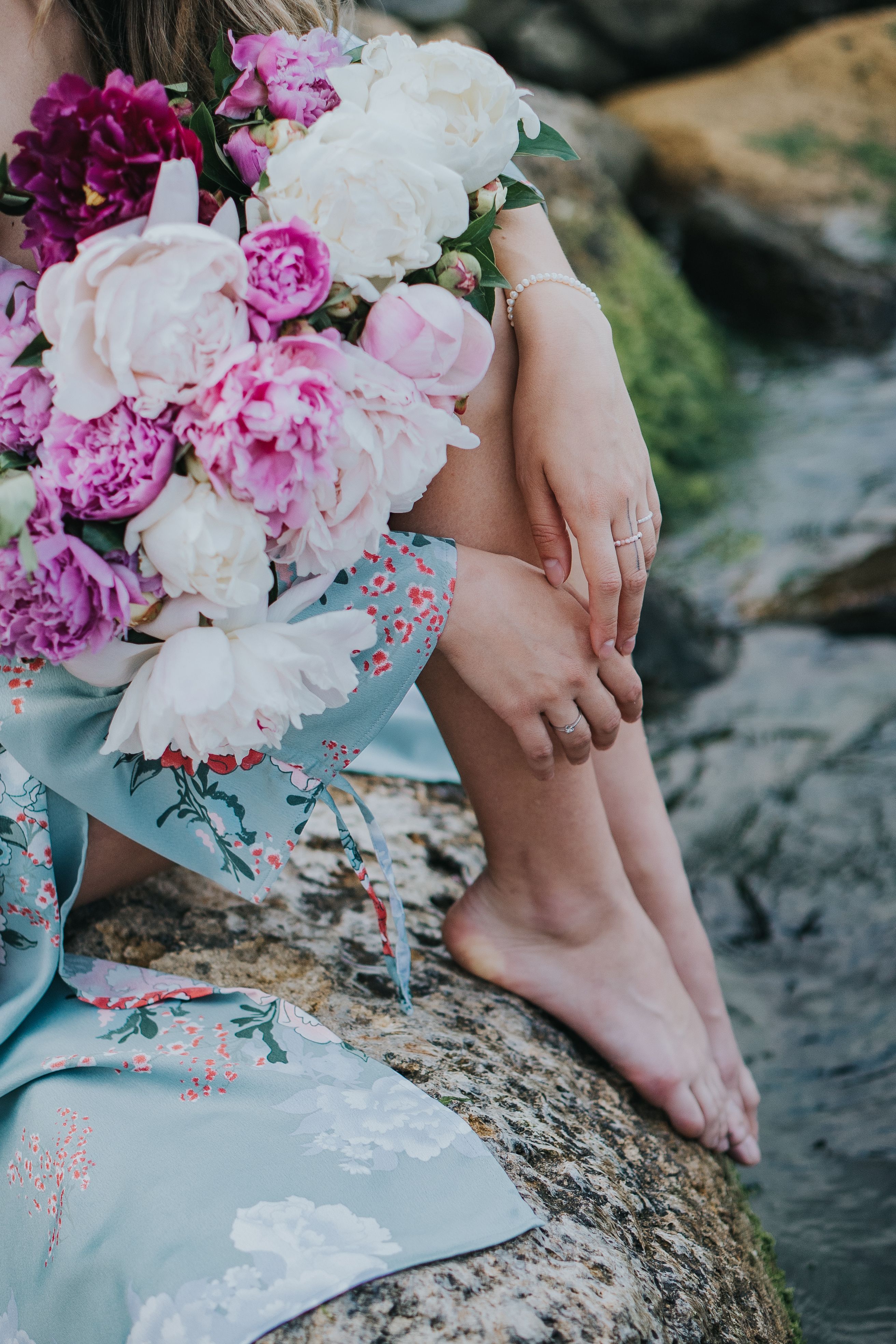 Woman with Flowers Sitting on Rock by River · Free Stock Photo