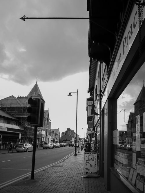Free Monochrome city street with shops and traffic, under overcast skies. Stock Photo