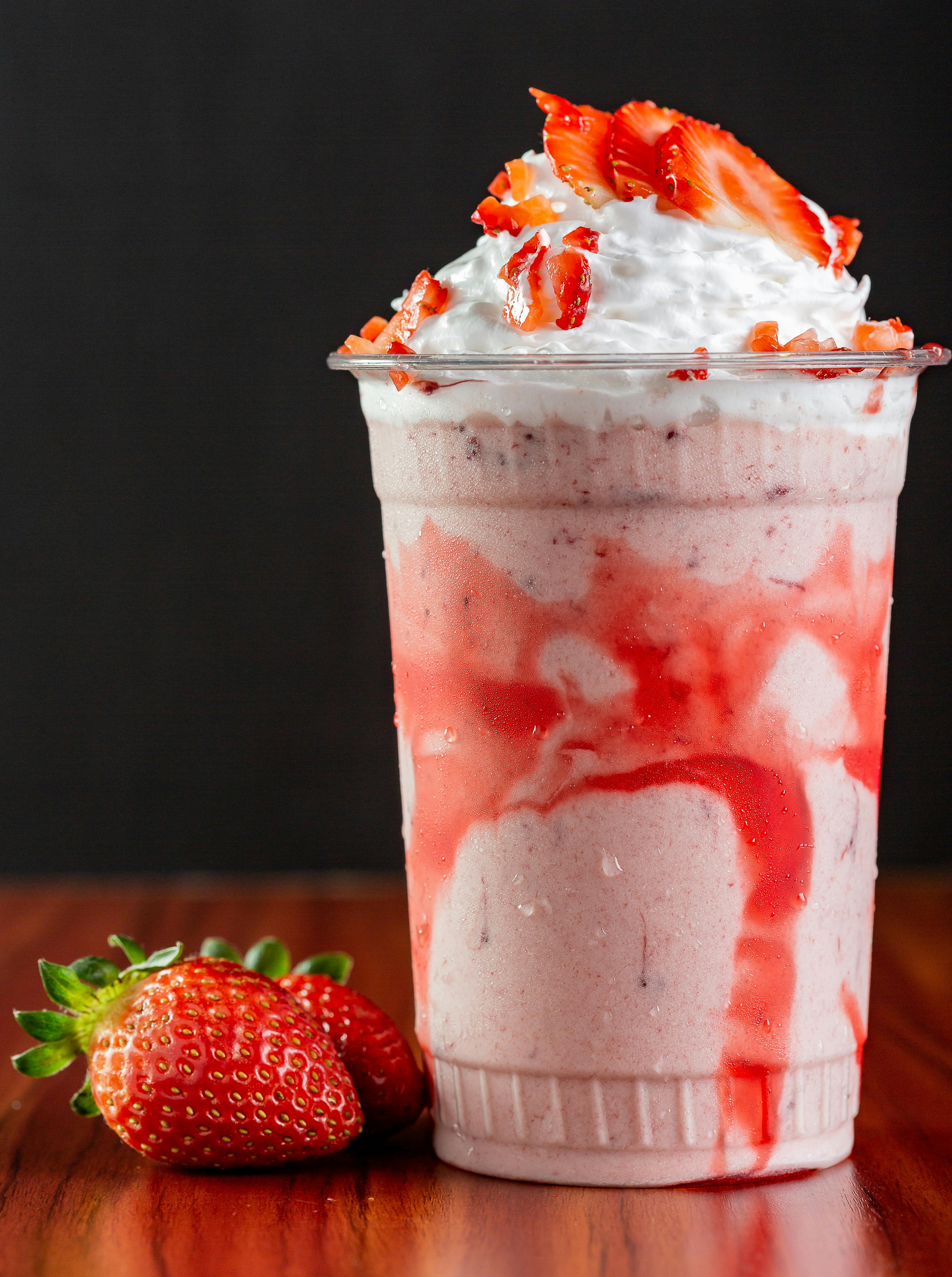 close up shot of strawberry milkshake with whipped cream In a