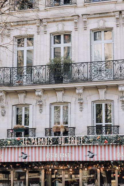 Beautiful facade of Le Paradis du Fruit restaurant in Paris with ornate balconies and elegant windows.