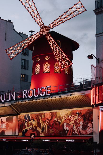 An illuminated view of the famous Moulin Rouge in Paris, showcasing its vibrant iconic windmill.