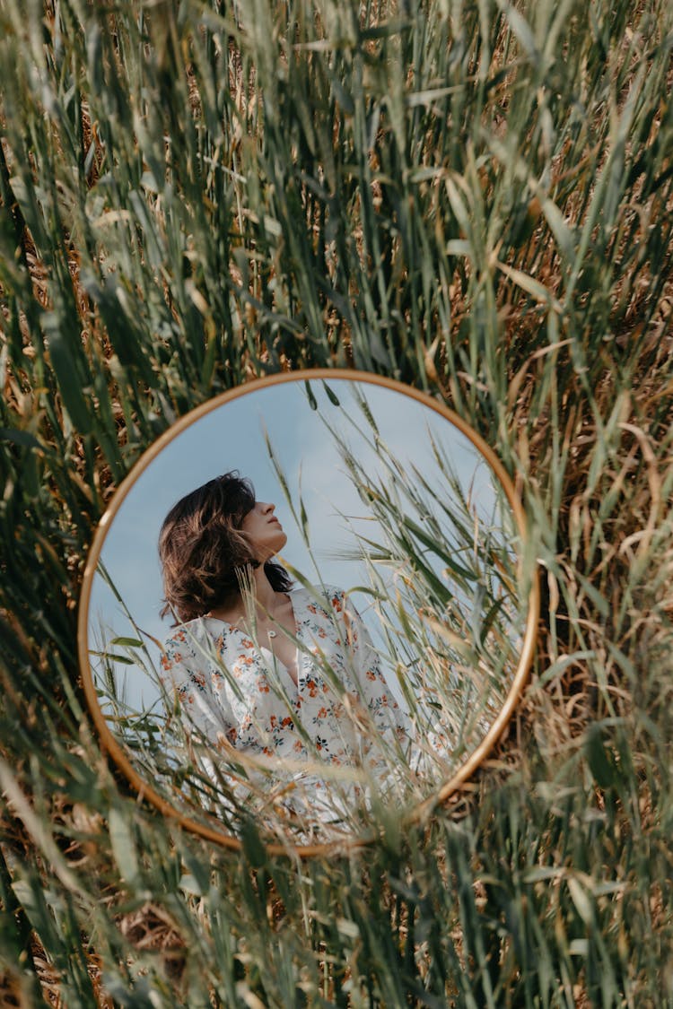 Woman Reflecting In Mirror In Field