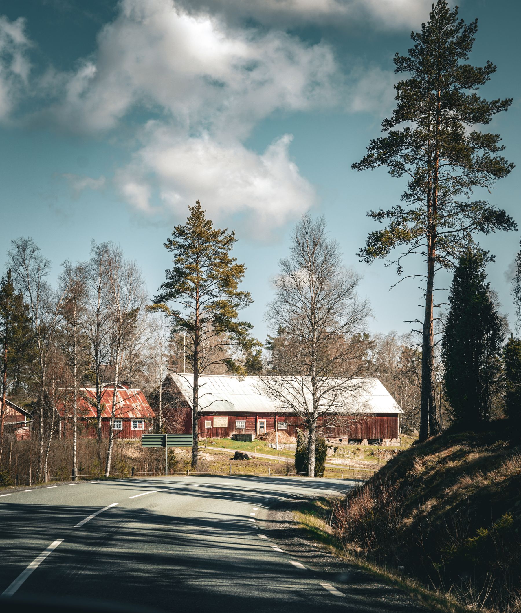 A quiet village road leading toward a farmhouse and trees