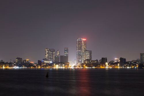 Free Captivating view of a city skyline at night, beautifully illuminated with glowing lights reflecting on water. Stock Photo