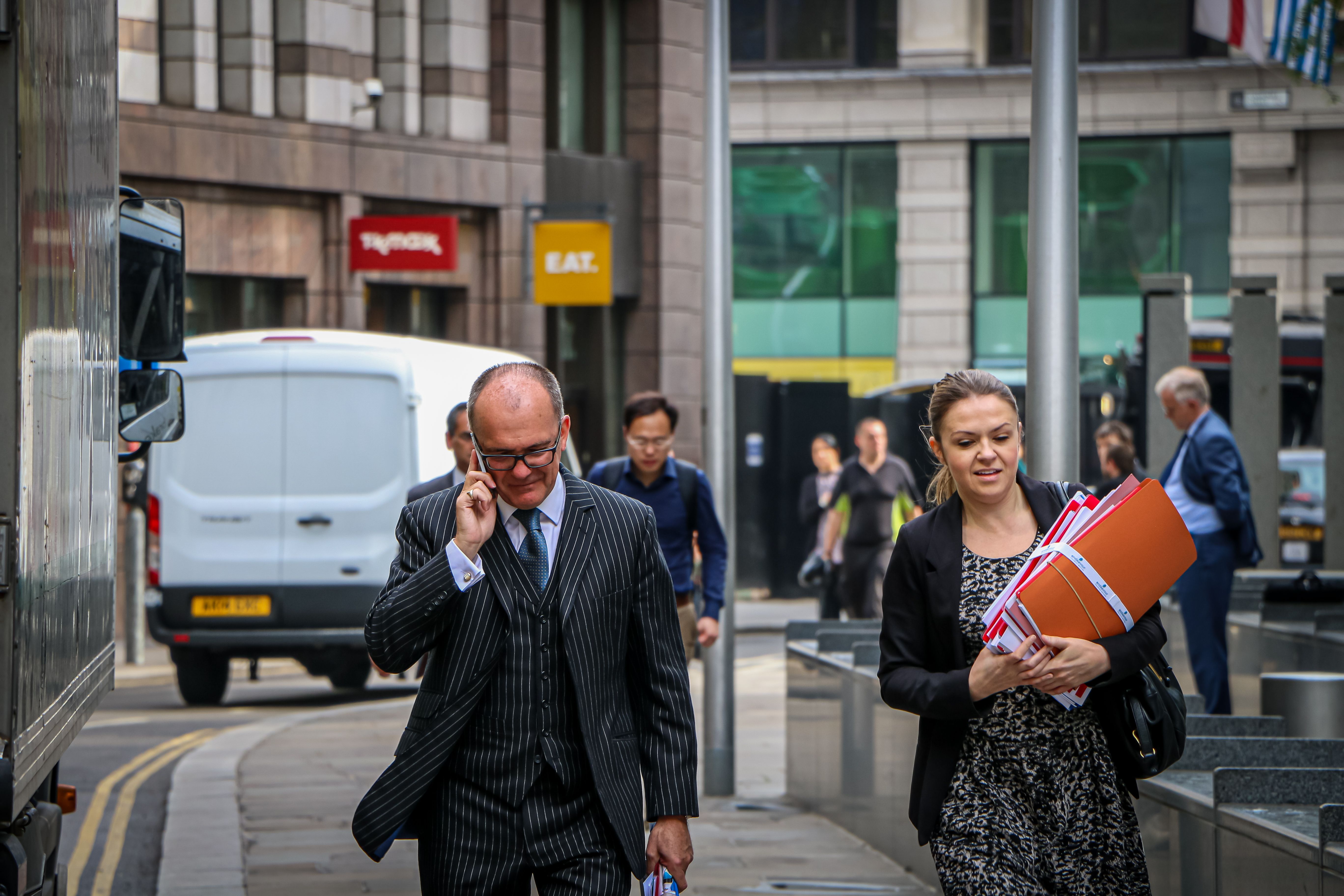 Businesspeople carrying documents while walking in a bustling city street. Urban business environment.
