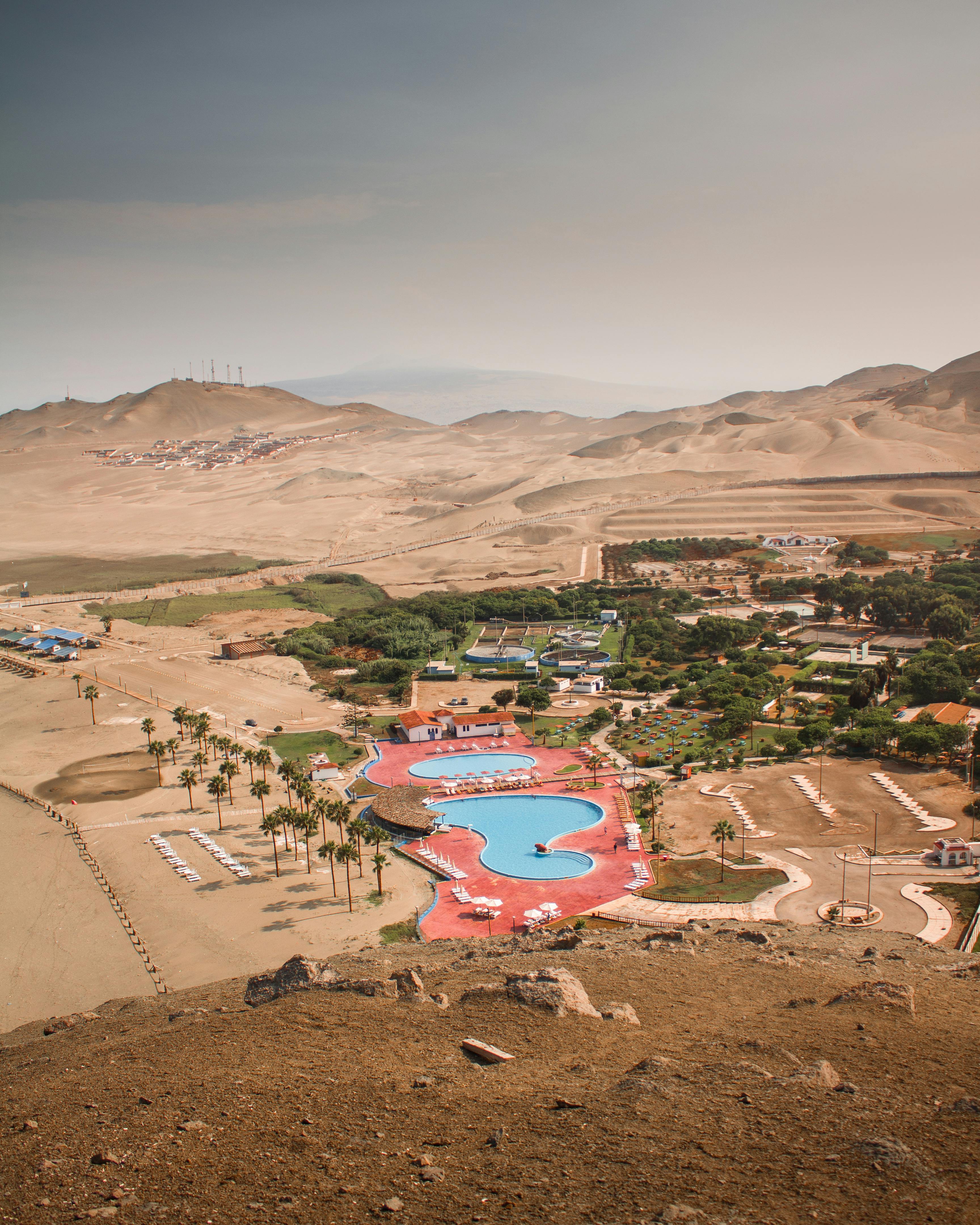 A stunning aerial view of an oasis resort nestled in the arid Lima desert landscape, Callao Region, Peru.