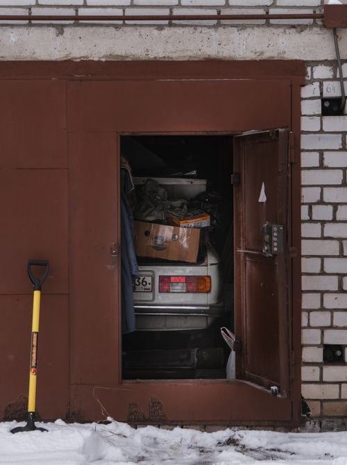 Free An open garage door reveals a forgotten car surrounded by snow and urban decay. Stock Photo