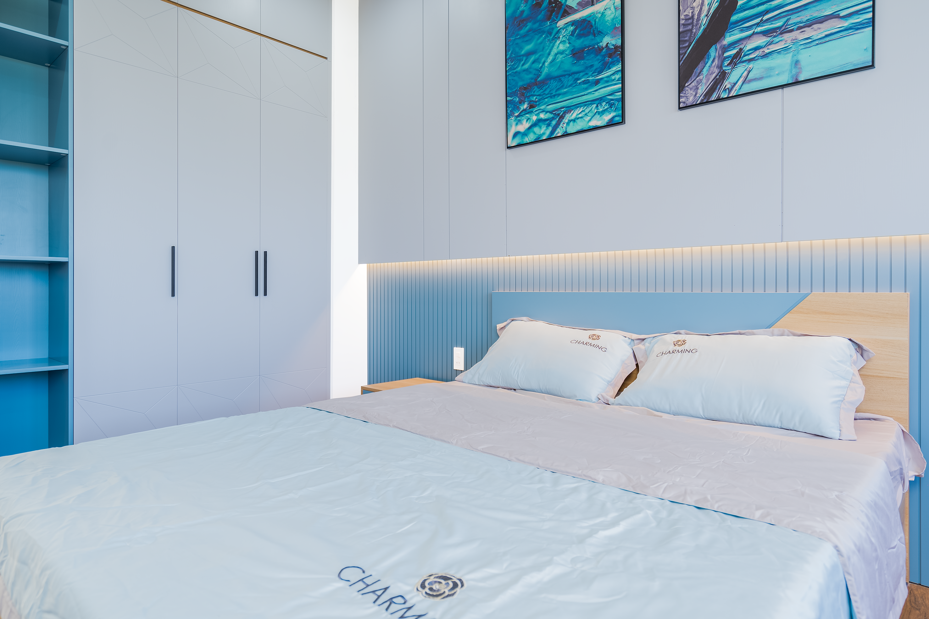 Elegant bedroom with blue accents featuring a cozy bed and modern art decor.