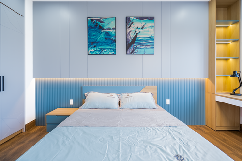 Free Stylish bedroom with blue decor, modern furnishings, and artistic wall art. Stock Photo