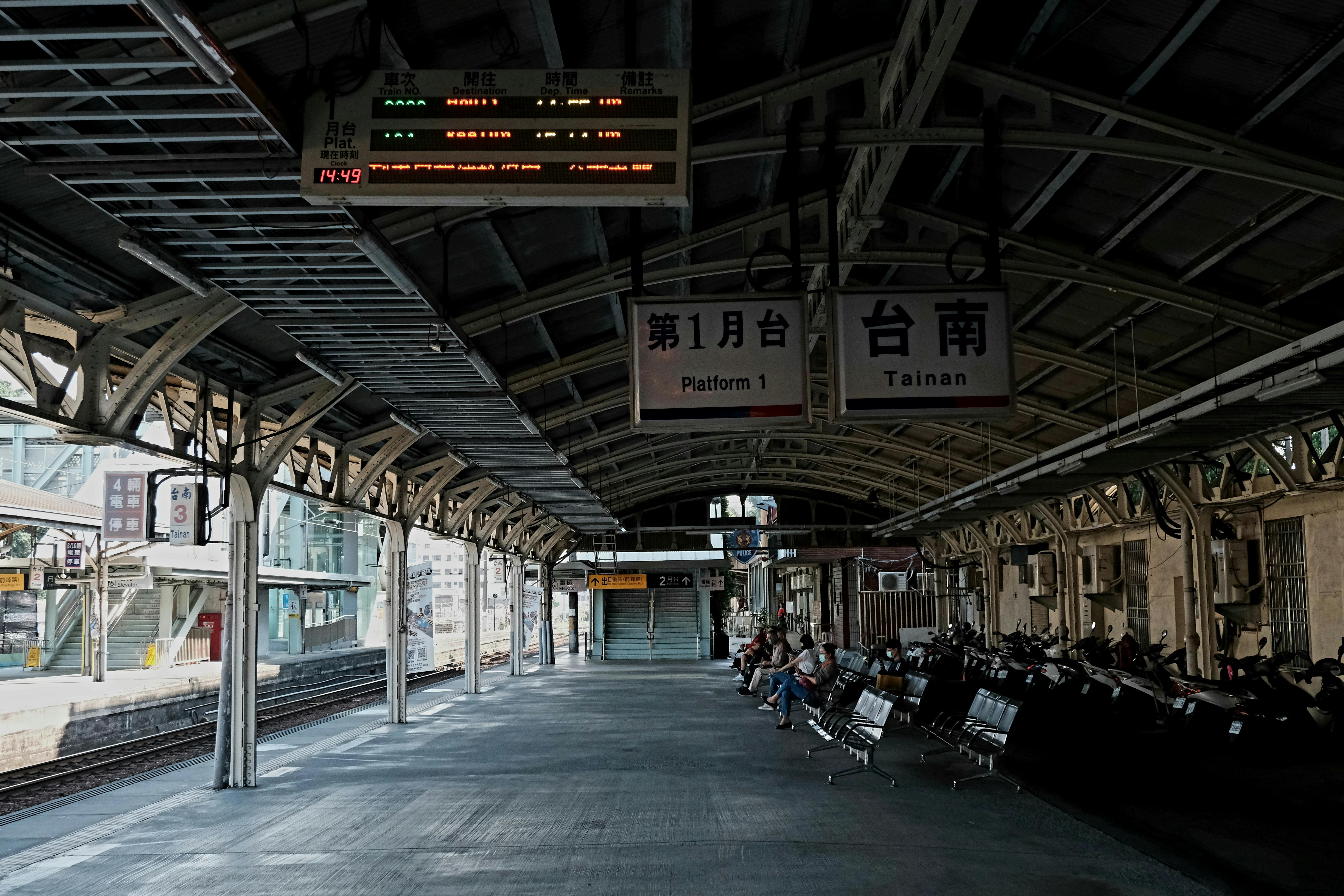 Empty train station platform in Tainan with benches and signs, creating a serene urban scene.