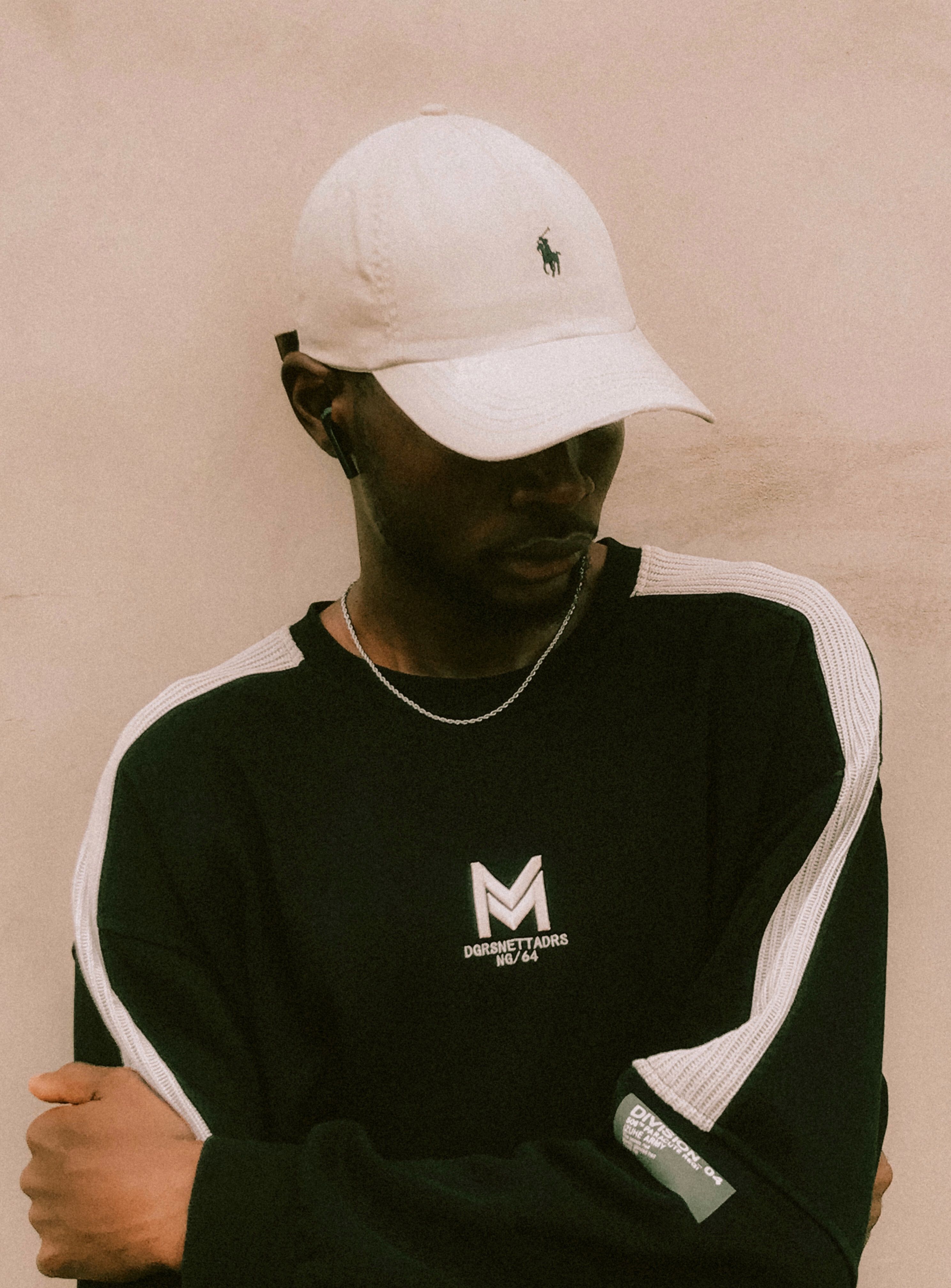 A fashionable young man wearing streetwear, captured with arms crossed, showcasing a casual and trendy look.