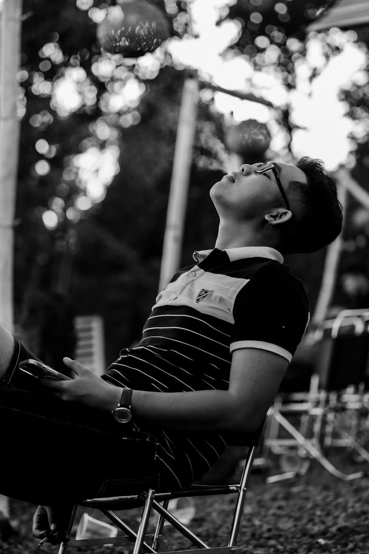 Grayscale Shot Of A Man Relaxing In A Garden