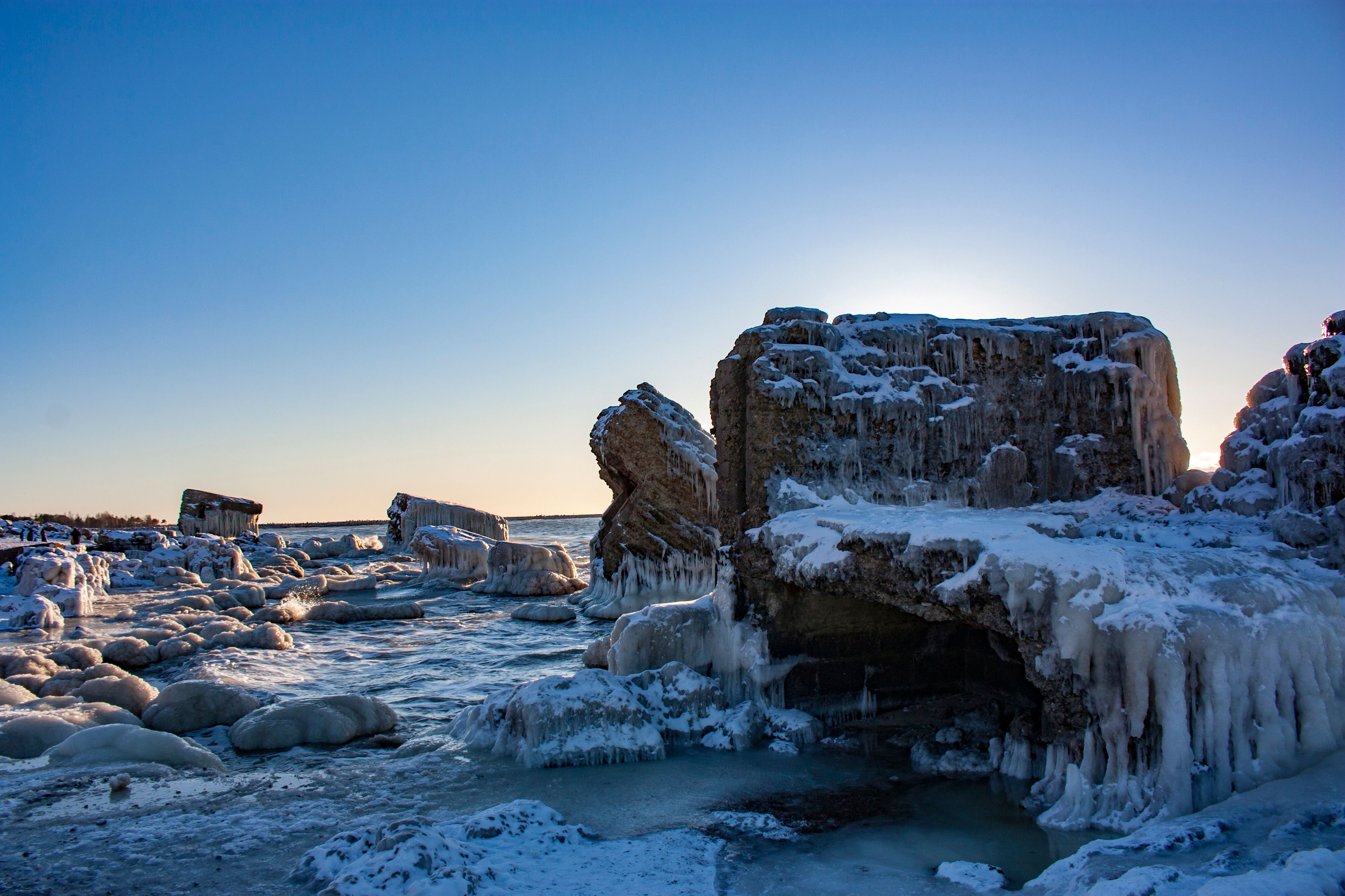 Majestic icy rock formations on a tranquil winter beach, bathed in sunrise light.