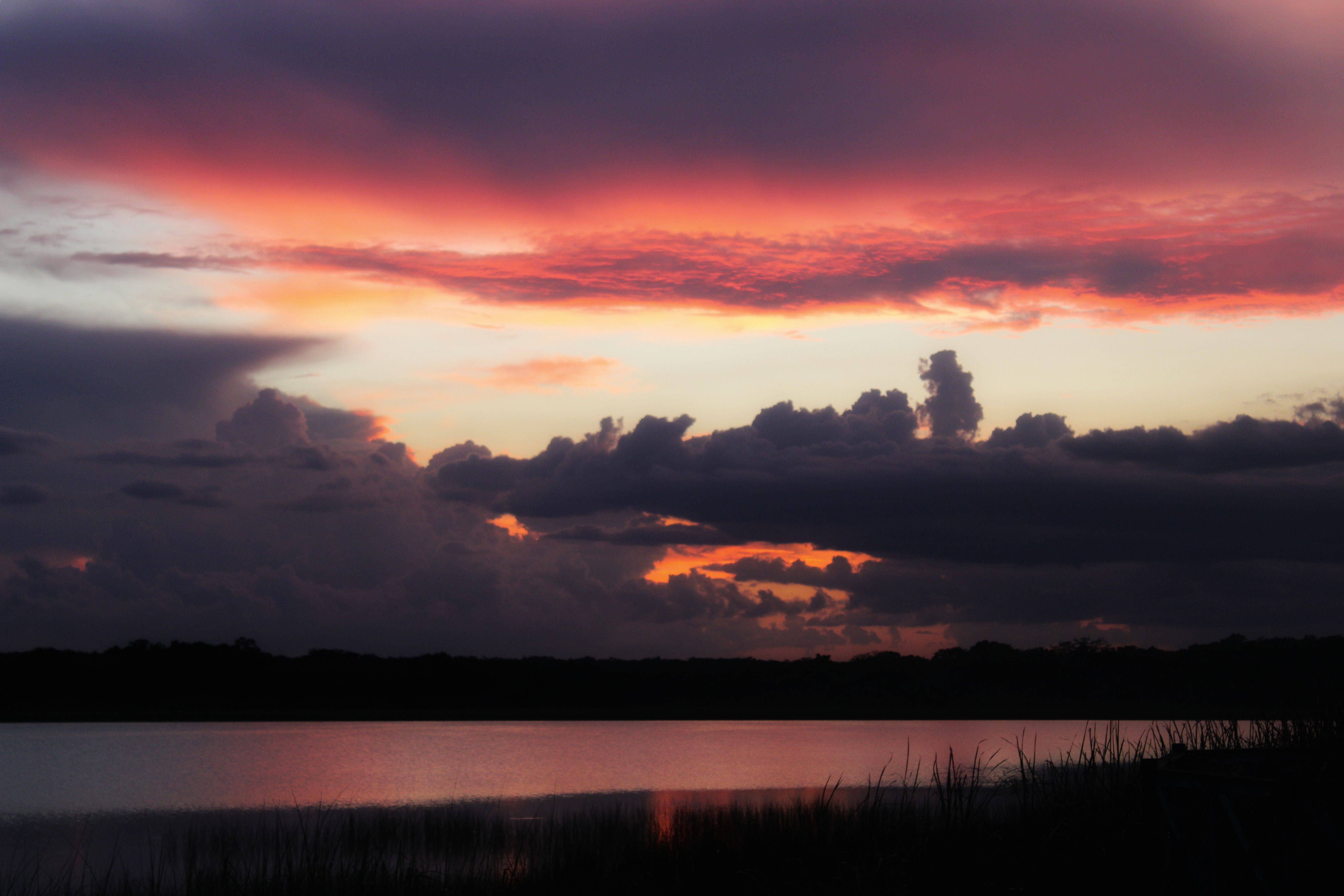 A sunset over a lake with clouds and water · Free Stock Photo